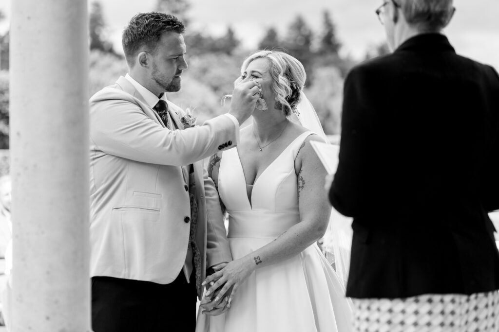 Groom wiping tears away from bride - Rhinefield House Hotel Wedding photographer for Ellie & Sam's wedding day