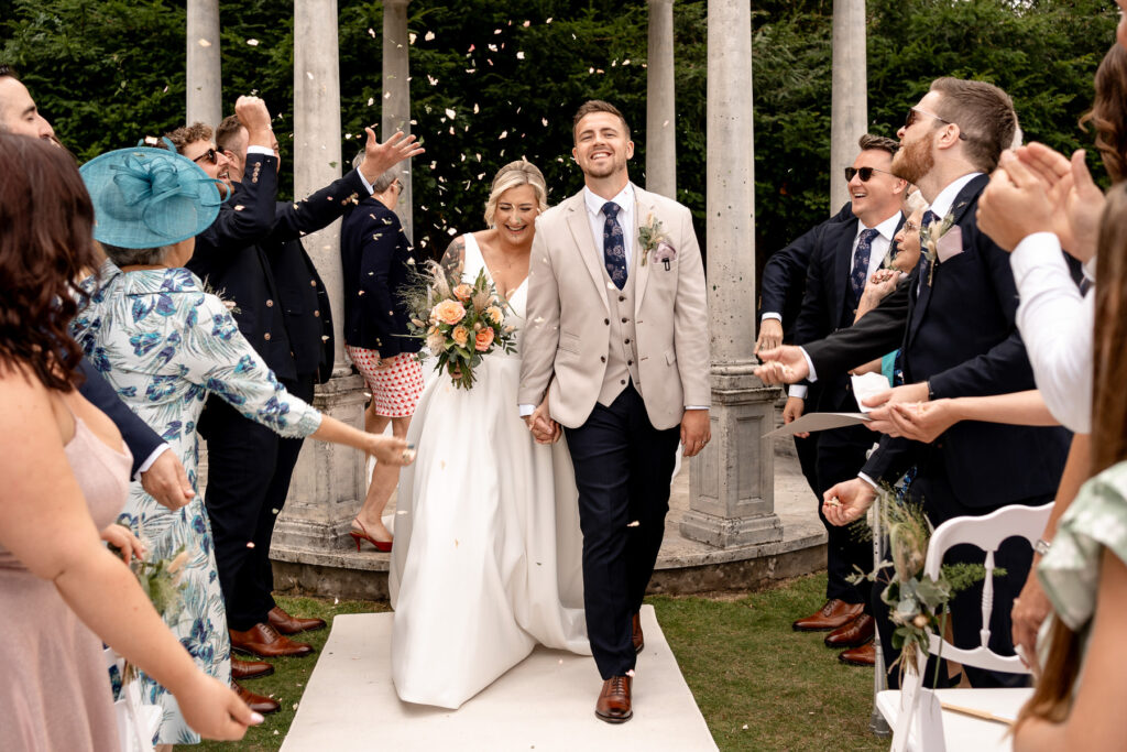 Bride and Groom walking through confetti laughing at Rhinefield House Hotel
