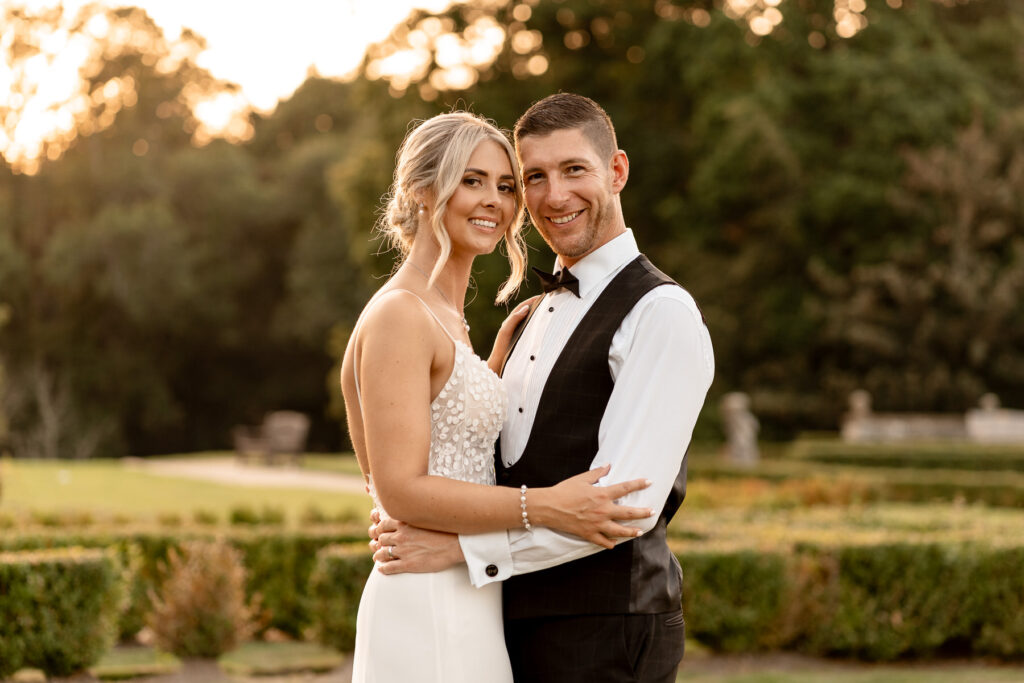 Bride and groom walking through the gardens at Rhinefield House during golden hour wedding photography.