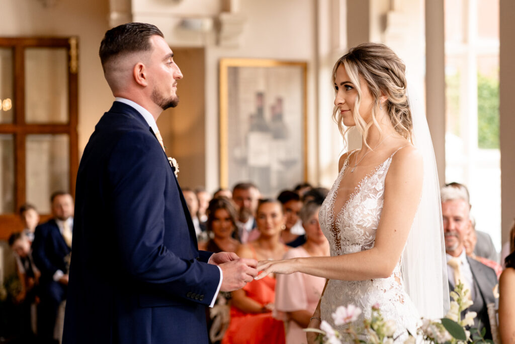 Groom putting on the Brides wedding ring at a Summer wedding at Audleys Wood