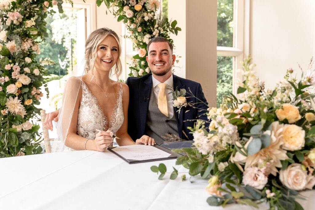 Bride and Groom signing the register at a Summer wedding at Audleys Wood