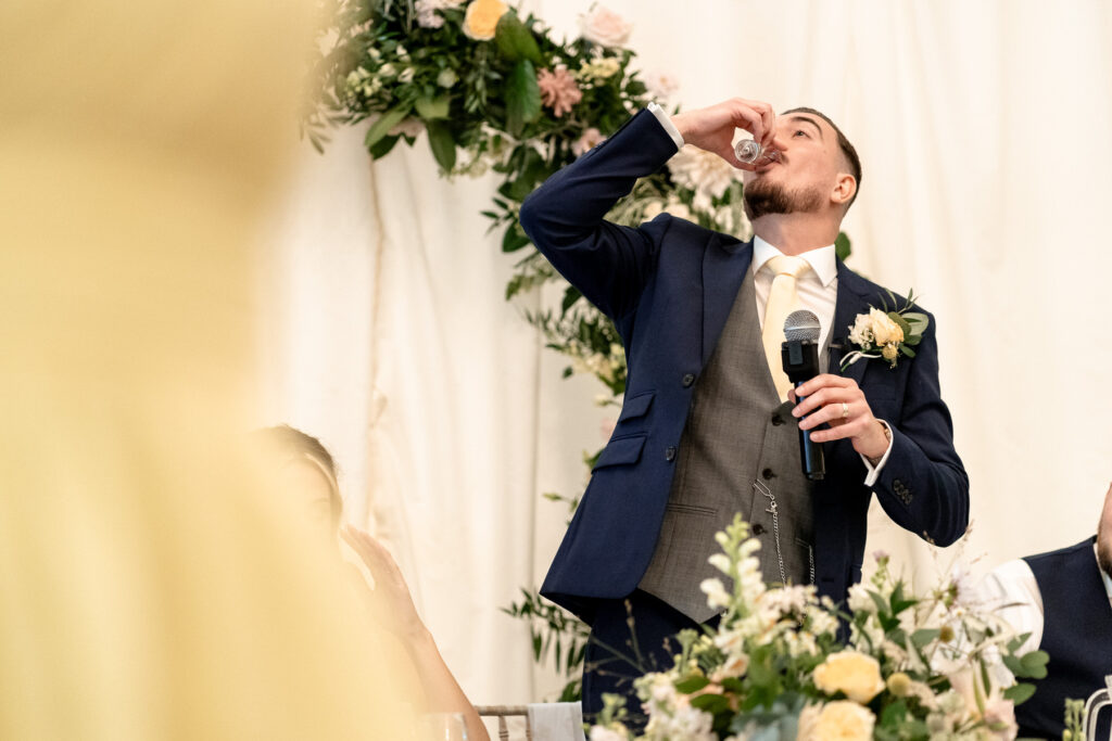 Groom having a shot at a Summer wedding at Audleys Wood
