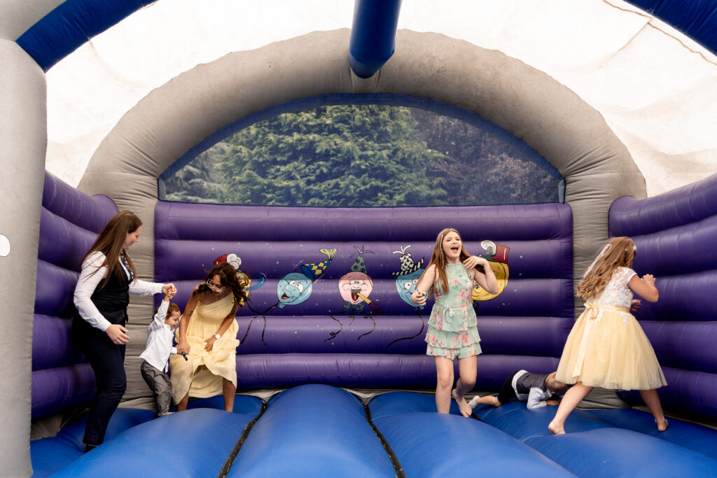 fun wedding inspiration at a Summer wedding at Audleys Wood - kids playing on a bouncy castle